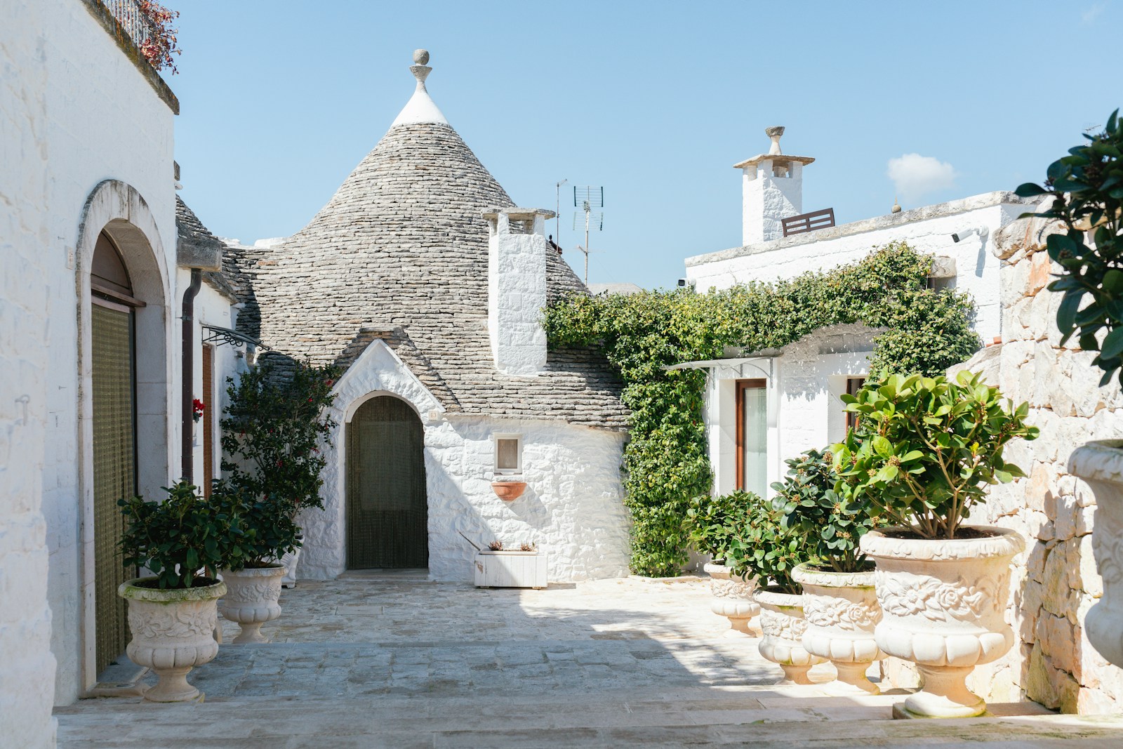 White trulli buildings in a sunny, italian courtyard.