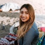 woman sitting on white, red, and black striped mat on top of stand